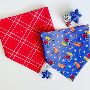 May include: Two dog bandanas. One is red with a white plaid pattern. The other is blue with a pattern of hot dogs on skateboards, stars, and rainbows. Decorative stars and a disco ball are also present.