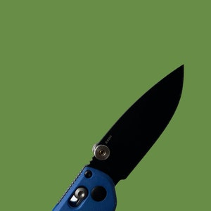 Puede incluir: Un cuchillo plegable negro con mango azul. La hoja está parcialmente abierta y el cuchillo tiene un pequeño botón plateado en el lateral. El texto "S90V" está grabado en la hoja.