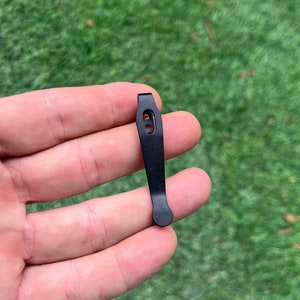 Op de afbeelding: Zwarte metalen zakclip met een afgerond uiteinde en een enkel gat.