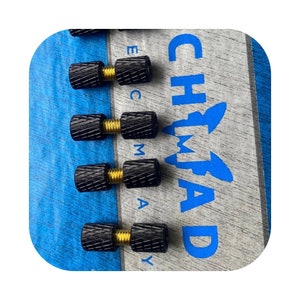 Puede incluir: Cuatro pomos roscados negros y dorados con un patrón de diamante. Los pomos están sobre un fondo azul y gris con el texto "CHIMAD" en azul.