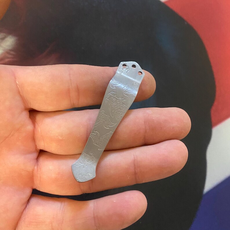 Pu&ograve; includere: Un fermaglio per tasca in argento con un motivo floreale decorativo. Il fermaglio ha tre fori nella parte superiore per fissarlo a una tasca.