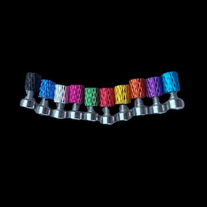 Könnte beinhalten: Ein Satz von 12 bunten Schraubkappen für Fahrradteile. Die Kappen sind in einem Regenbogen von Farben, darunter Schwarz, Blau, Weiß, Pink, Grün, Rot, Gelb, Orange, Lila und Türkis.