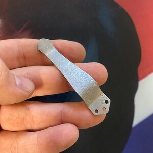 Pu&ograve; includere: Un fermaglio per tasca in argento con un design floreale inciso. Il fermaglio ha tre fori per fissarlo a una tasca.