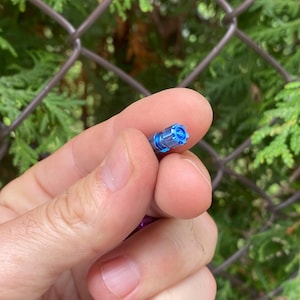 May include: Close-up of a blue metal valve stem with a star-shaped cap.