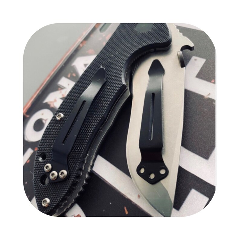 May include: A black and silver pocket knife with a black pocket clip. The knife has a textured handle and a partially serrated blade.