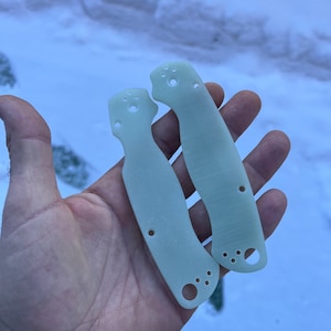 May include: Two white plastic knife scales with multiple holes. The scales are designed for a folding knife.