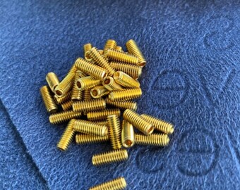May include: A pile of gold-colored screws on a blue textured surface. The screws are all the same size and have a slightly rounded head.