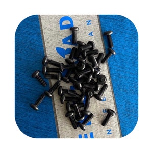 May include: A large pile of black screws on a blue and white wooden surface.