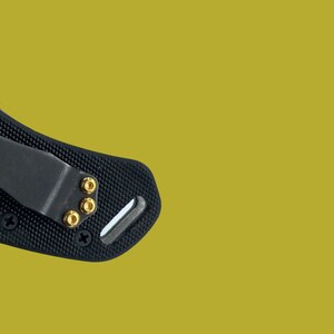 Puede incluir: Clip de bolsillo negro para cuchillo con tornillos dorados. El clip est&aacute; hecho de un material texturizado y tiene una forma curva.