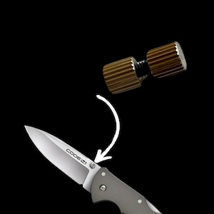 May include: A silver pocket knife with a black handle and the word "CODE 1" engraved on the blade. A gold metal screw with a threaded design is shown above the knife.