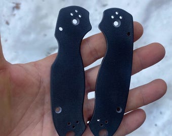 May include: Two black plastic knife scales with a paw print design and multiple holes.
