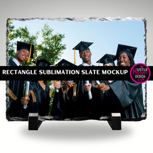 May include: A black slate rectangle with a photo of a group of graduates in black caps and gowns holding diplomas. The slate is on a stand and has a white background.
