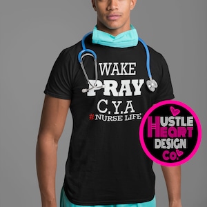 May include: A black t-shirt with the text "WAKE PRAY C.Y.A. #NURSE LIFE" in white. A stethoscope is draped around the neck of the shirt. A pink circle with the text "HUSTLE HEART DESIGN CO." in white is in the lower right corner of the image.