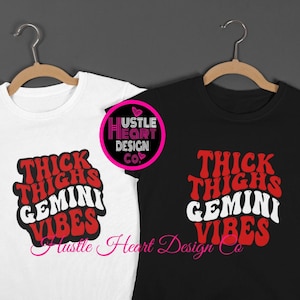 Puede incluir: Dos camisetas con el texto "Thick Thighs Gemini Vibes" en letras rojas y blancas sobre un fondo blanco y negro. Las camisetas están colgadas en perchas.