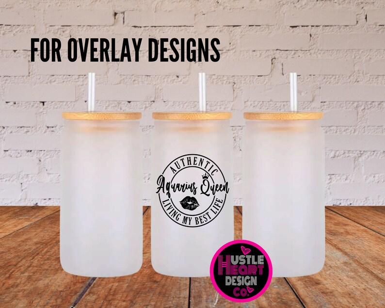 May include: Three frosted glass tumblers with bamboo lids and straws. The middle tumbler has a black and white graphic that says "Authentic Aquarius Queen Living My Best Life" with a crown and a red lip print.