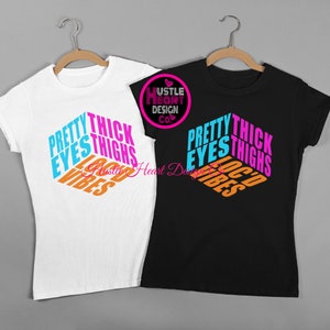 May include: Two t-shirts with the text "Pretty Eyes Thick Thighs Loc'd Vibes" in a colorful, 3D-style design. The shirts are white and black.