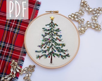 May include: Embroidered Christmas tree with colorful beads and sequins in a wooden embroidery hoop. The hoop is on a white surface with a red and black plaid fabric and a silver star.