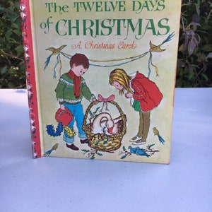 May include: A vintage Little Golden Book titled "The Twelve Days of Christmas: A Christmas Carol". The cover features a boy and girl in winter clothing looking at a basket with a goose inside. The book is red and white with a green and white border.