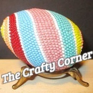 May include: A colorful crocheted Easter egg with stripes of red, yellow, blue, pink, and white.
