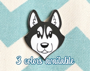 May include: Black and white enamel pin of a cartoon husky dog's face. The pin has a glossy finish and is about 1 inch in diameter.