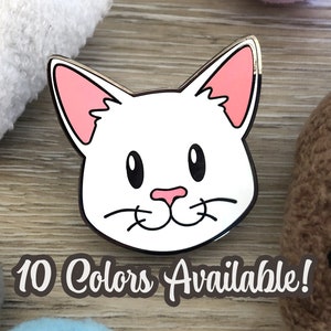 May include: White enamel pin with a cartoon cat face. The cat has pink ears and a pink nose. The pin is 10 colors available.