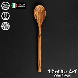 Könnte beinhalten: Ein Holzlöffel aus Olivenholz mit langem Stiel und abgerundeter Schüssel. Der Löffel hat ein natürliches Holzmaserungsmuster und der Text "What the Art! Olive Wood" ist sichtbar. Das Bild enthält auch den Text "100% Natural Product" und "Italian Olive Wood".