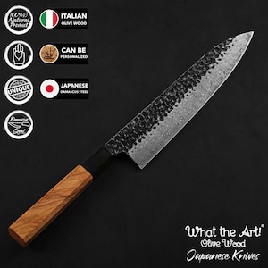 Puede incluir: Un cuchillo japonés de acero de Damasco con mango de madera de olivo. La hoja tiene un acabado texturizado y oscuro, y el mango es de color marrón claro. El cuchillo está etiquetado como "What the Art! Olive Wood Japanese Knives."