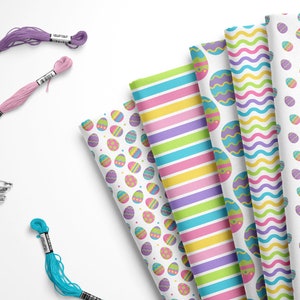 May include: Five different fabric patterns featuring Easter egg designs. The patterns include a white background with colorful eggs, a striped pattern with pink, yellow, green, and blue stripes, a wavy pattern with blue, green, and purple waves, a pattern with colorful eggs on a white background, and a pattern with colorful eggs on a white background.