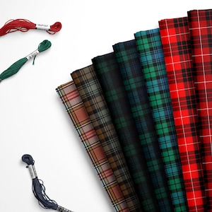 May include: Assortment of plaid fabrics in various colors, including red, green, and blue. The fabrics are arranged in a fan shape, with the red plaid fabric at the top and the blue plaid fabric at the bottom. There are also spools of thread in red, green, and blue.