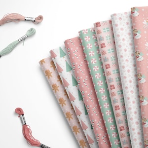 May include: A collection of patterned paper rolls in pastel colors, featuring Christmas-themed designs like gingerbread men, candy canes, and nutcrackers. Three spools of embroidery floss in pink and green are also present.