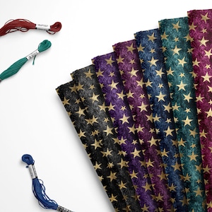 May include: A collection of eight fabric swatches featuring a repeating pattern of gold stars on a dark background. The fabric swatches are arranged in a fan shape, with the colors ranging from dark blue to burgundy.