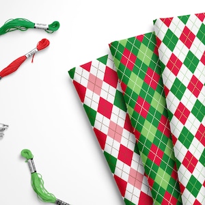 May include: Four different fabric swatches with a red and green argyle pattern. The swatches are arranged in a fan shape. There are also two spools of green thread and one spool of red thread.