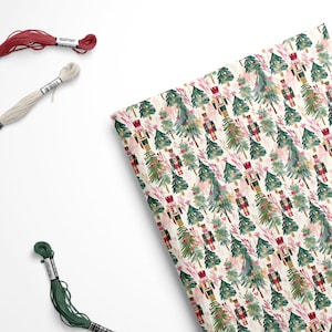 May include: A white fabric with a repeating pattern of watercolor nutcrackers and Christmas trees. The nutcrackers are wearing red and gold uniforms and the trees are green with pink accents.