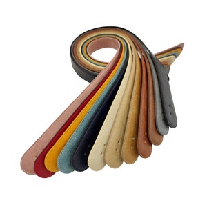 Könnte beinhalten: Ein Set mit 12 bunten Wildledergürteln in verschiedenen Brauntönen, Gelb, Rot, Blau und Beige. Die Gürtel sind fächerförmig angeordnet, wobei die Enden der Gürtel nach rechts zeigen.