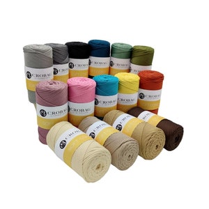 Könnte beinhalten: Eine Sammlung von 16 Spulen mit weichem Baumwollgarn in verschiedenen Farben, darunter Grau, Schwarz, Türkis, Grün, Gelb, Orange, Rosa und Braun. Jede Spule ist mit dem Markennamen "CROBAG" und dem Text "SOFT CORD" gekennzeichnet.
