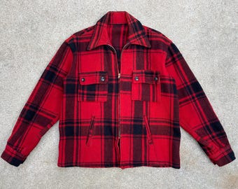 May include: A red and black plaid flannel shirt with a zipper closure. The shirt has two chest pockets and a single pocket on the left side.