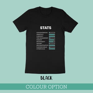 May include: A black short-sleeved t-shirt featuring the white text STATS at the top, followed by a list of attributes including concentration, creativity, curiosity, time management, passion, spontaneity, memory, procrastination, planning skills, and hyperfocus, each paired with a horizontal progress bar.