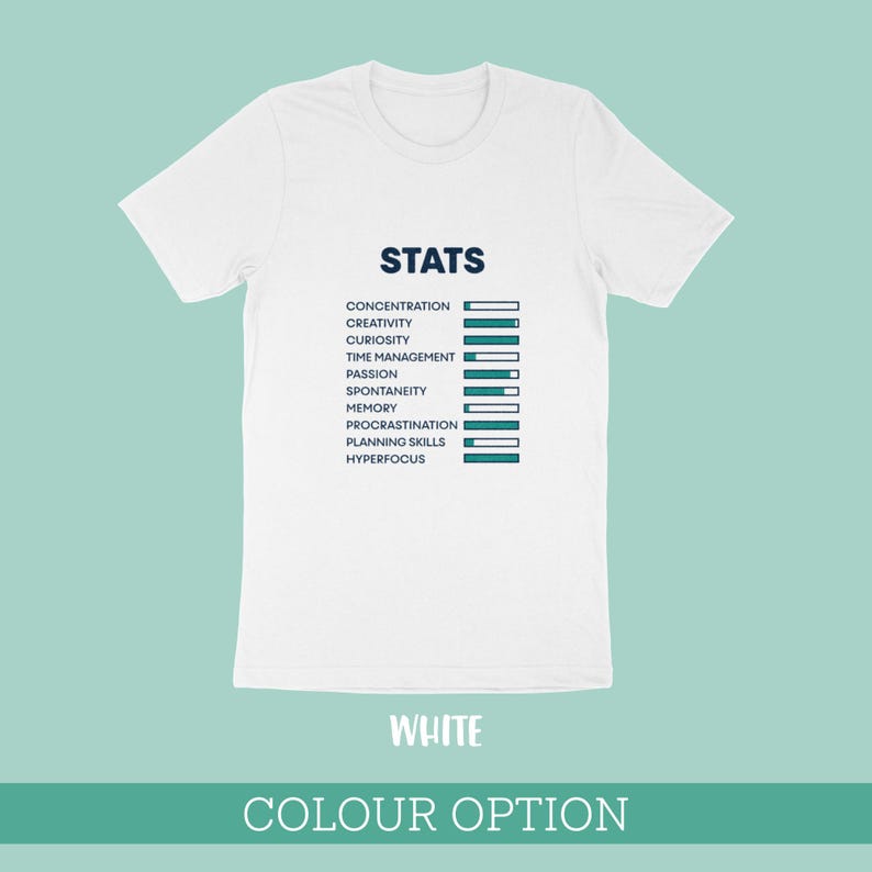May include: A white short-sleeved t-shirt featuring a dark blue graphic titled STATS. The design displays a list of attributes including concentration, creativity, curiosity, time management, passion, spontaneity, memory, procrastination, planning skills, and hyperfocus, each paired with a horizontal progress bar.