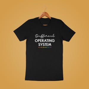 Może przedstawiać: Czarny T-shirt z białym tekstem, kt&oacute;ry brzmi "Different Operating System" i rzędem tęczowych symboli nieskończoności pod tekstem.