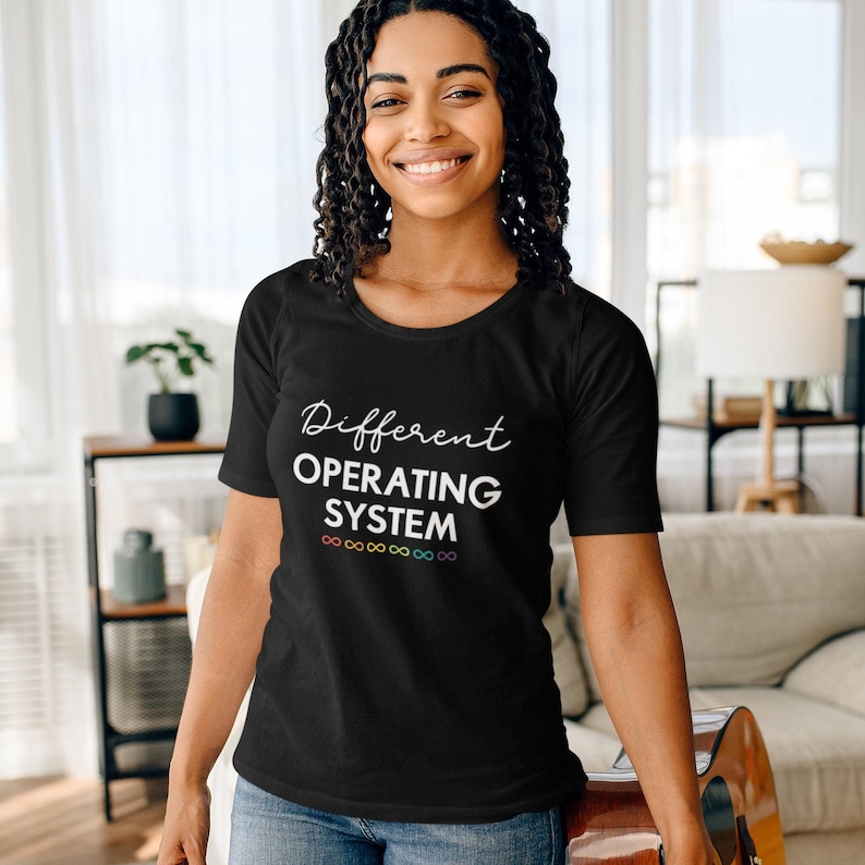 Może przedstawiać: Czarny T-shirt z białym tekstem, kt&oacute;ry brzmi "Different Operating System" z tęczą symboli nieskończoności pod tekstem.