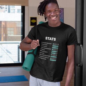 May include: A black short-sleeved t-shirt featuring the white text "STATS" above a list of attributes including concentration, creativity, curiosity, time management, passion, spontaneity, memory, procrastination, planning skills, and hyperfocus.