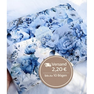 Könnte beinhalten: Ein Paket, das in florales Papier mit großen blauen und weißen Blumen eingewickelt ist. Das Papier hat einen Aquarelleffekt, wobei die Blumen in verschiedenen Blautönen gehalten sind. Ein Etikett mit dem Text "VON HERZEN" ist sichtbar.