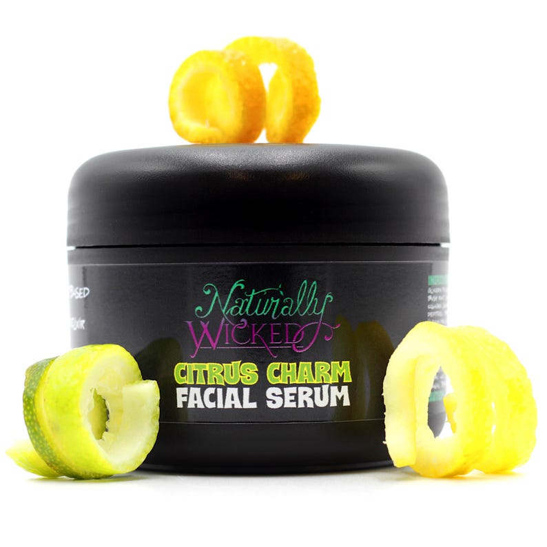 Naturally Wicked Citrus Charm Serum in sleek black packaging, garnished with spirals of lemon and lime.