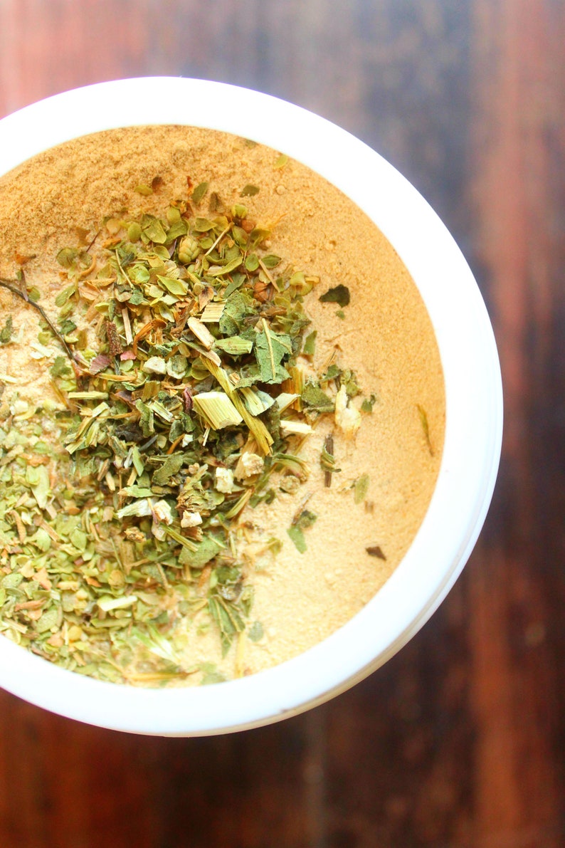 Puede incluir: Un taz&oacute;n blanco lleno de un polvo marr&oacute;n claro y hierbas verdes. Las hierbas son una mezcla de hojas y tallos secos.