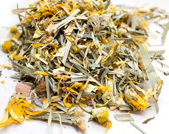Könnte beinhalten: Nahaufnahme einer getrockneten Kräutertee-Mischung mit gelben Calendula-Blütenblättern, grünen Zitronengras-Stücken und anderen getrockneten Kräutern.
