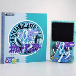 Op de afbeelding: Een Game Boy Color console en bijpassende doos, beide met een Pokemon-ontwerp. De doos en console hebben een cirkelvormige afbeelding van een Pokemon-personage. De doos leest "Game Boy Color" en "Pokemon" in het Engels en Japans.