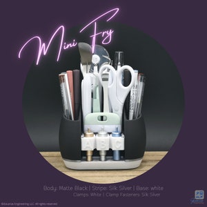 May include: A black and white organizer labeled "Mini Fry" with various craft tools. The organizer has a white base and holds pens, scissors, and other tools. The text "Mini Fry" is in a neon pink script.