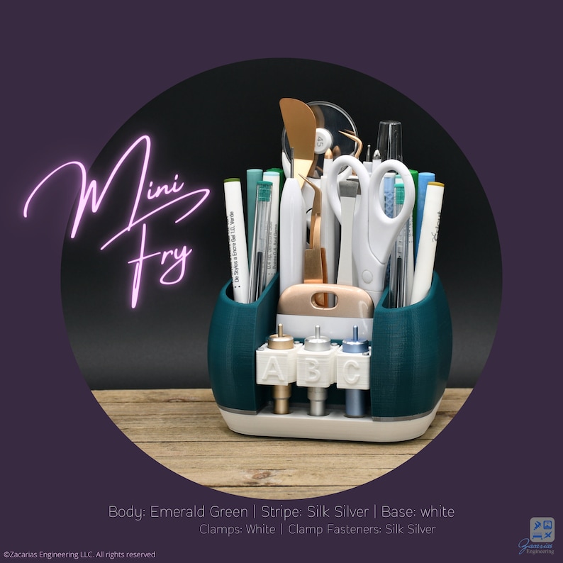 May include: A teal desk organizer labeled "Mini Fry" holds various craft tools, including scissors, pens, and tweezers. The organizer has a white base and silver accents. The text "ABC" is visible on the front, along with the Zacarias Engineering LLC logo.