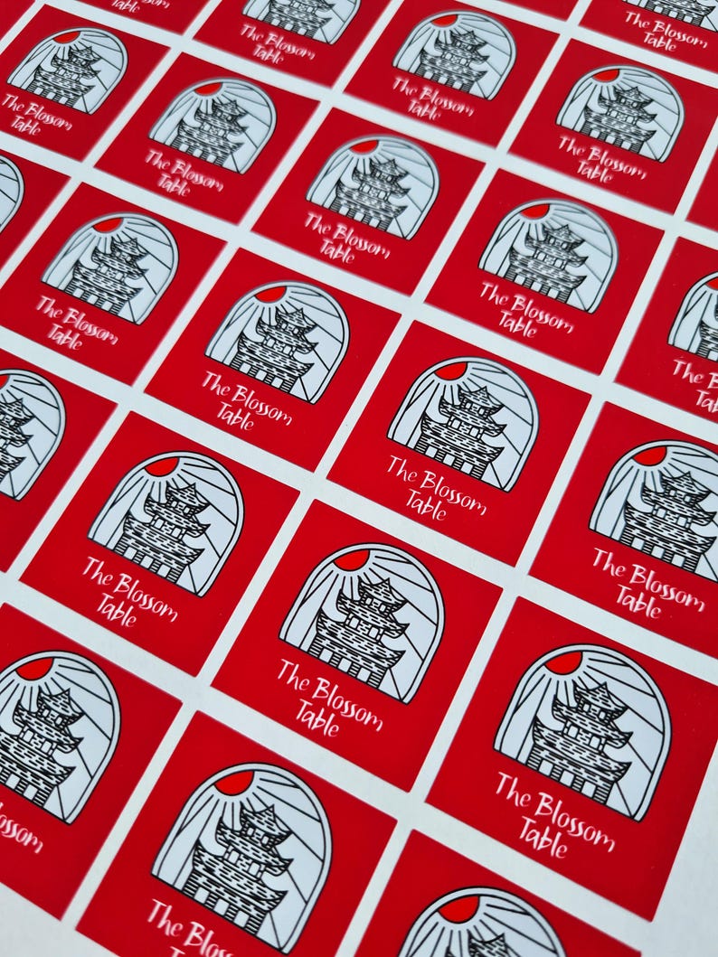 May include: A sheet of red square stickers with a white pagoda-like building design and the text "The Blossom Table" repeated on each sticker.