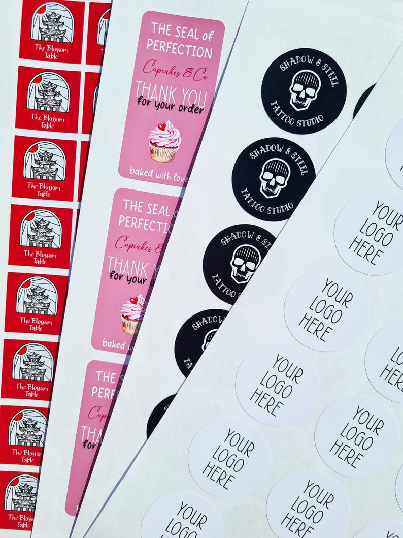 May include: Assortment of stickers featuring various designs.  The stickers include a pink cupcake with the text "The Seal of Perfection Cupcakes & Co. Thank You for your order. Baked with love."  Other stickers feature a skull and crossbones with the text "Shadow & Steel Tattoo Studio" and a white circle with the text "Your Logo Here".